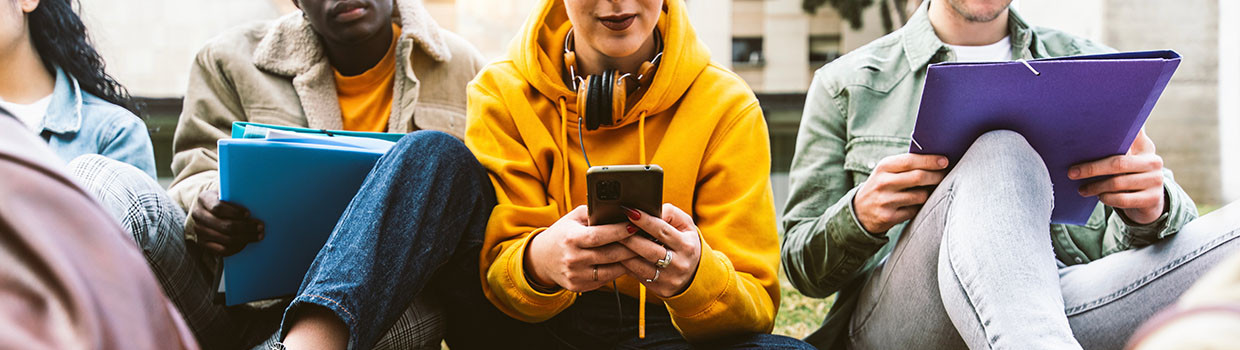 Photo étudiants ou lycéens à l'extérieur assis avec télphone sac et documents