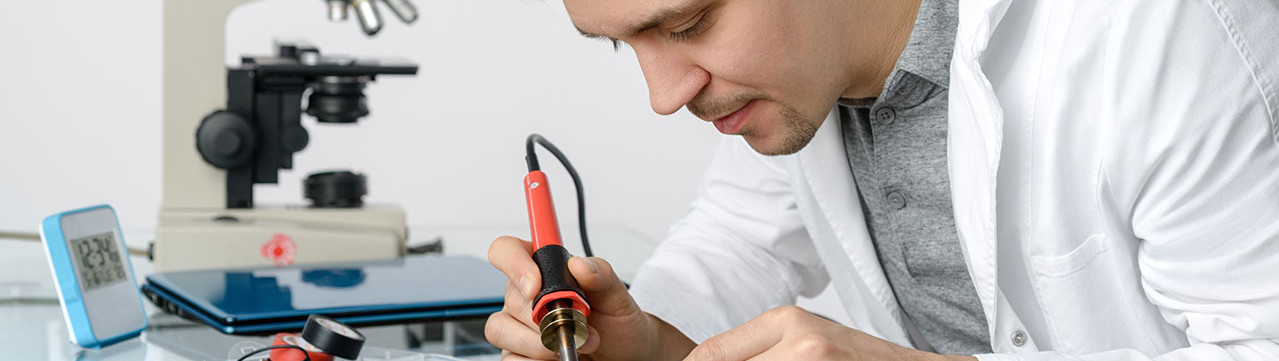 Photo jeune technicien informatique soudant des composants électroniques enseignement professionnel apprenti