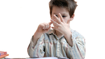 photo jeune élève compte sur ses doigts un cahier posé devant lui mathématiques ecole elementaire premier degre