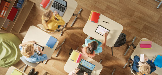 photo de classe vue de dessus avec orfinateur et tablette sur les tables numérique