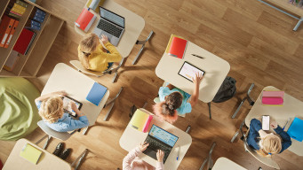 photo de classe vue de dessus avec orfinateur et tablette sur les tables numérique