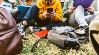 Photo étudiants ou lycéens à l'extérieur assis avec télphone sac et documents