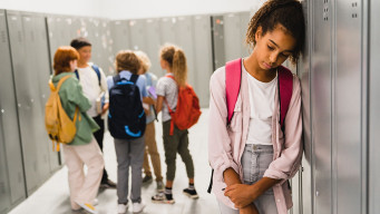 photo fille isolée dans un couloir face à un groupe d'élèves victime de harcèlement