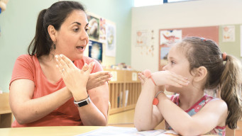 photo élève parle en langue des signes avec une professeur dans la classe handicap inclusion