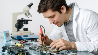 Photo jeune technicien informatique soudant des composants électroniques enseignement professionnel apprenti