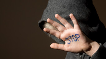 Photo main d'enfant avec le mot stop harcèlement discrimination