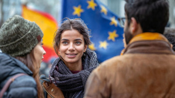 Jeunes discutant avec un drapeau de l'Union européenne en fond